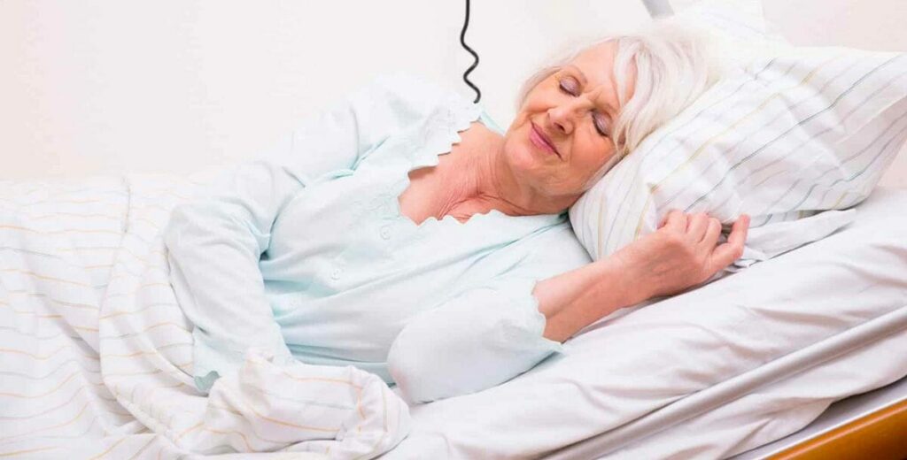 Mujer mayor descansa sobre una cama articulada con colchon antiescaras de ortofix